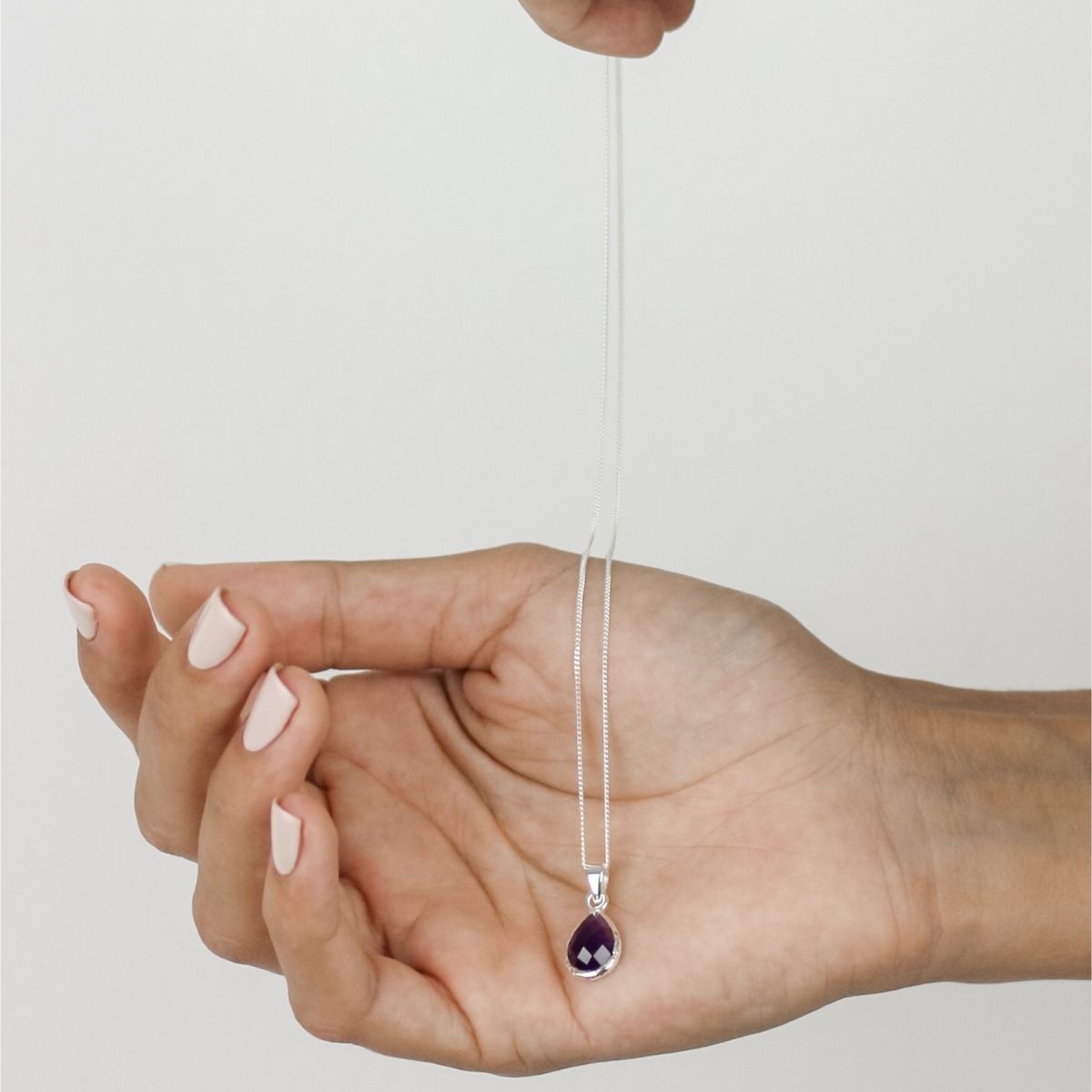 a woman holding a purple pendant in her hand