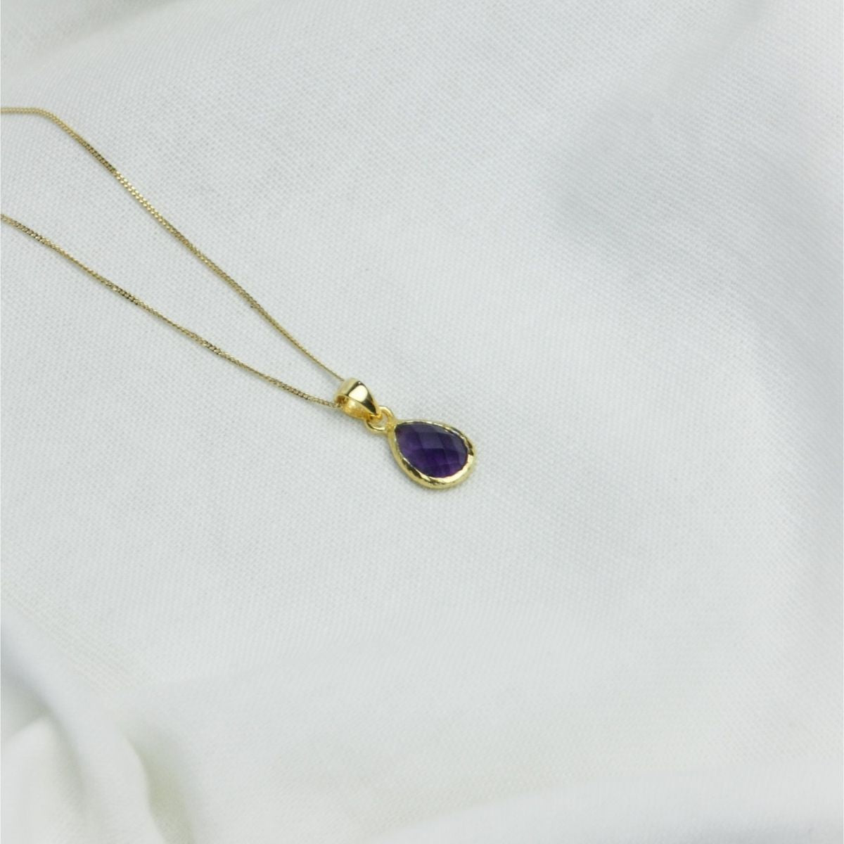 a purple pendant necklace on a white cloth