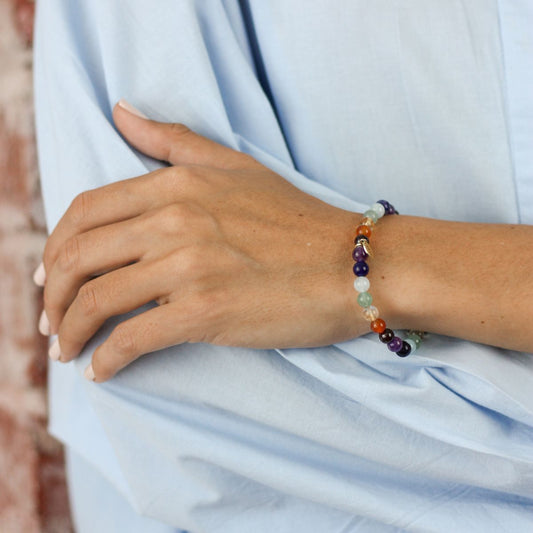 a woman folding her arm wearing a chakra bracelet on her wrist