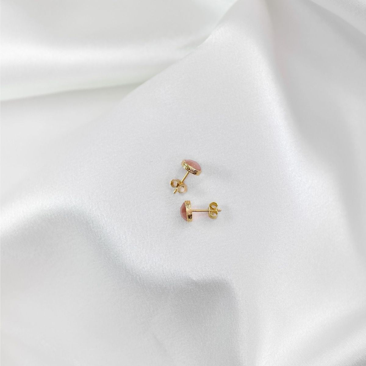 a pair of peach moonstone studs on a white cloth