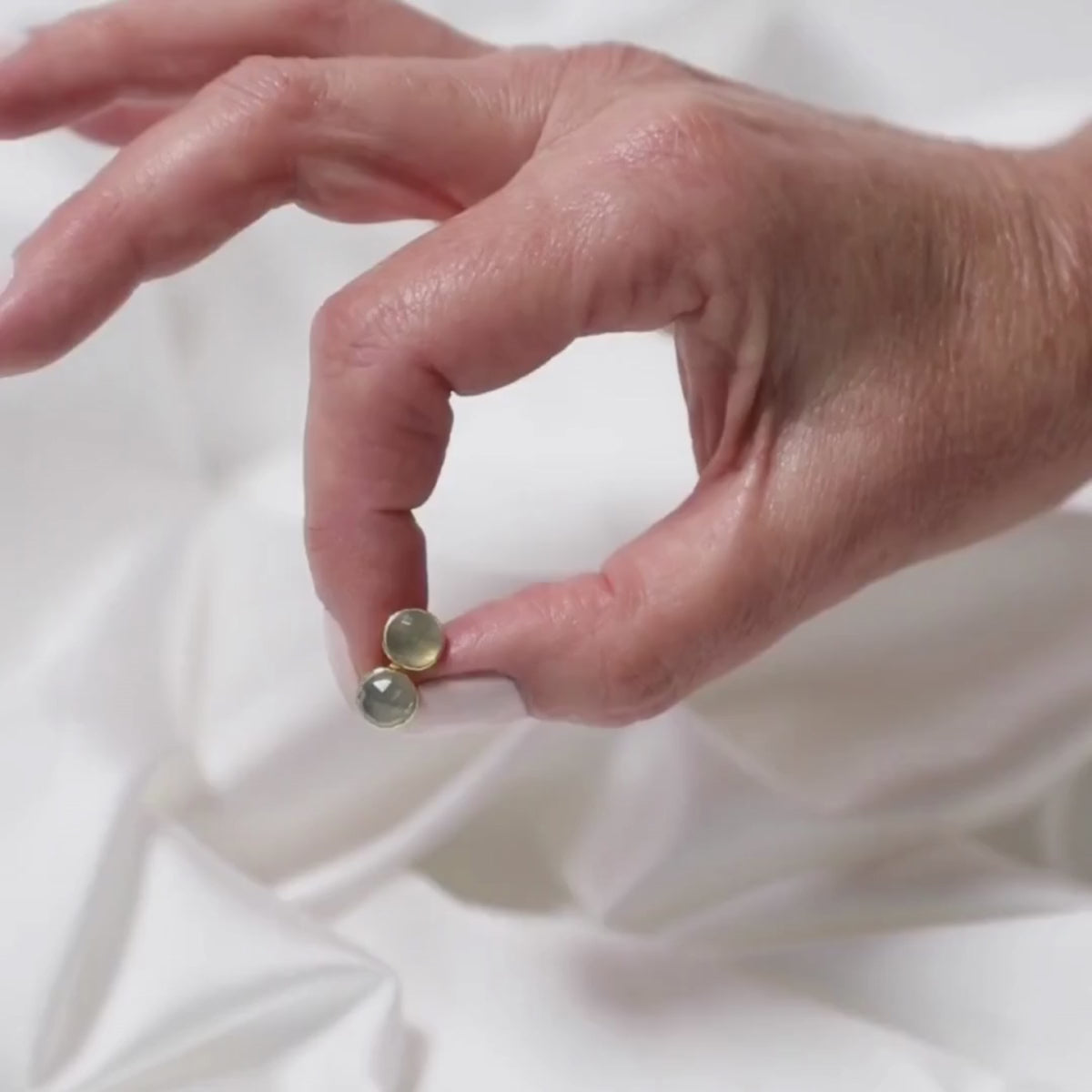 a woman holding studs in between her fingers