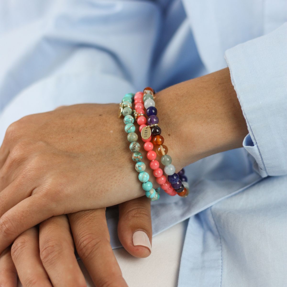 a woman wearing stone bracelets on her arm